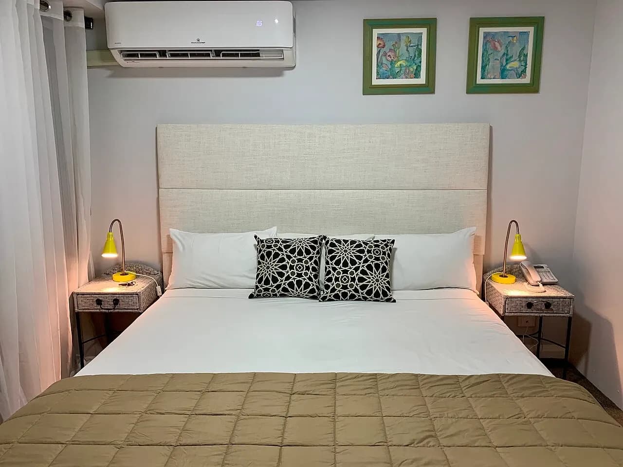 Bed, padded headboard, bedside furniture and wall-mounted cooling unit in a bedroom