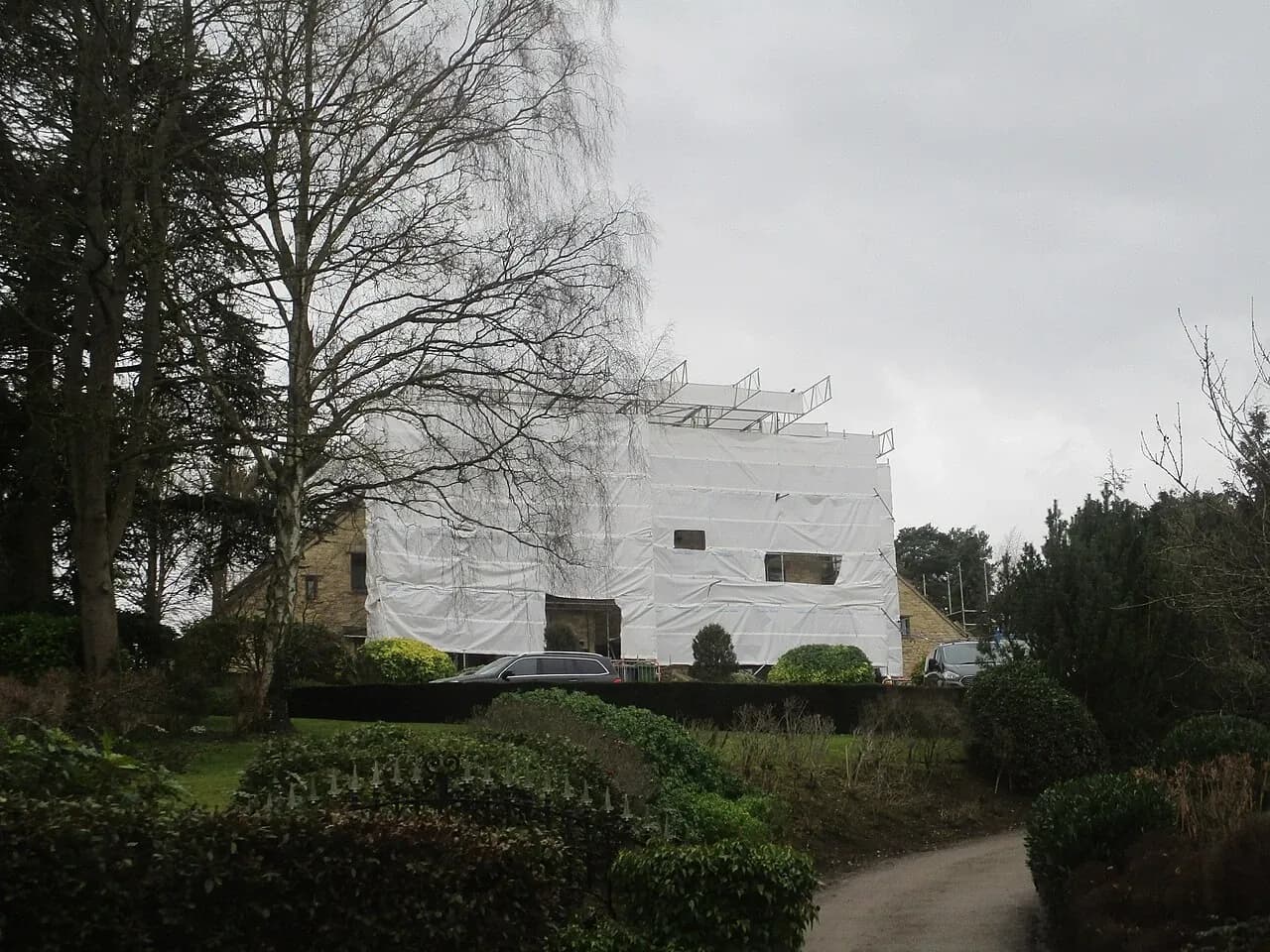 House covered by white sheeting and scaffolding during renovation in Linton, West Yorkshire, England