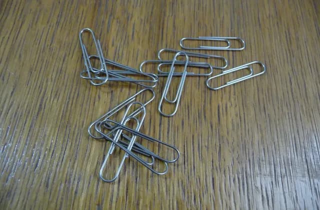 Silver-coloured paper clips scattered on a wood-patterned surface