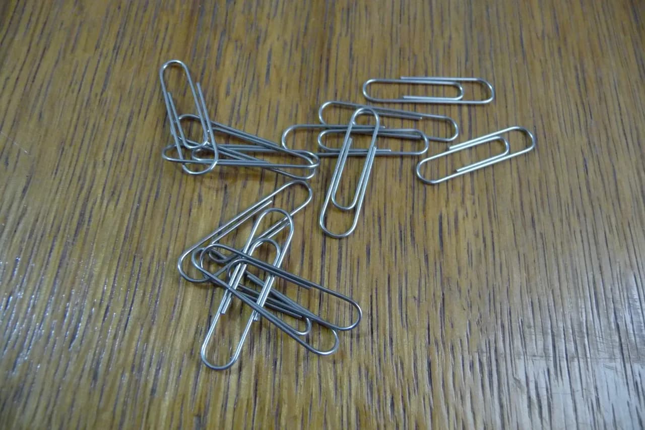 Silver-coloured paper clips scattered on a wood-patterned surface