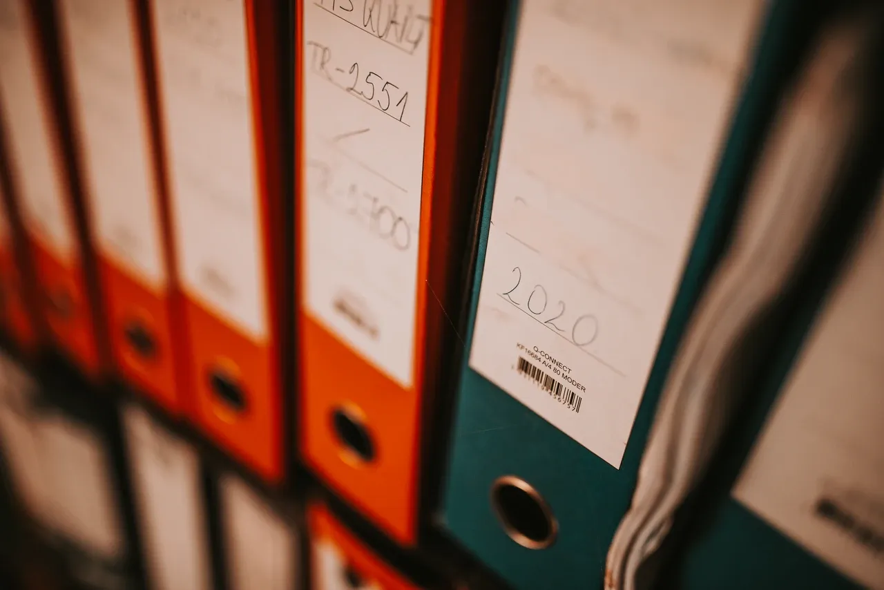 Orange and green document binders on a shelf, photographed by Nenad Stojkovic in October 2021