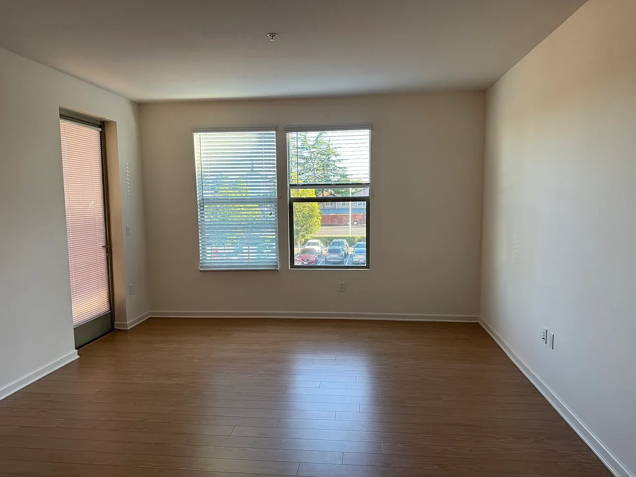 Unfurnished apartment room with a window, glazed outside door and wall sockets