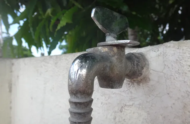 Weathered wall-mounted tap with a handle against a pale wall, photographed in July 2017