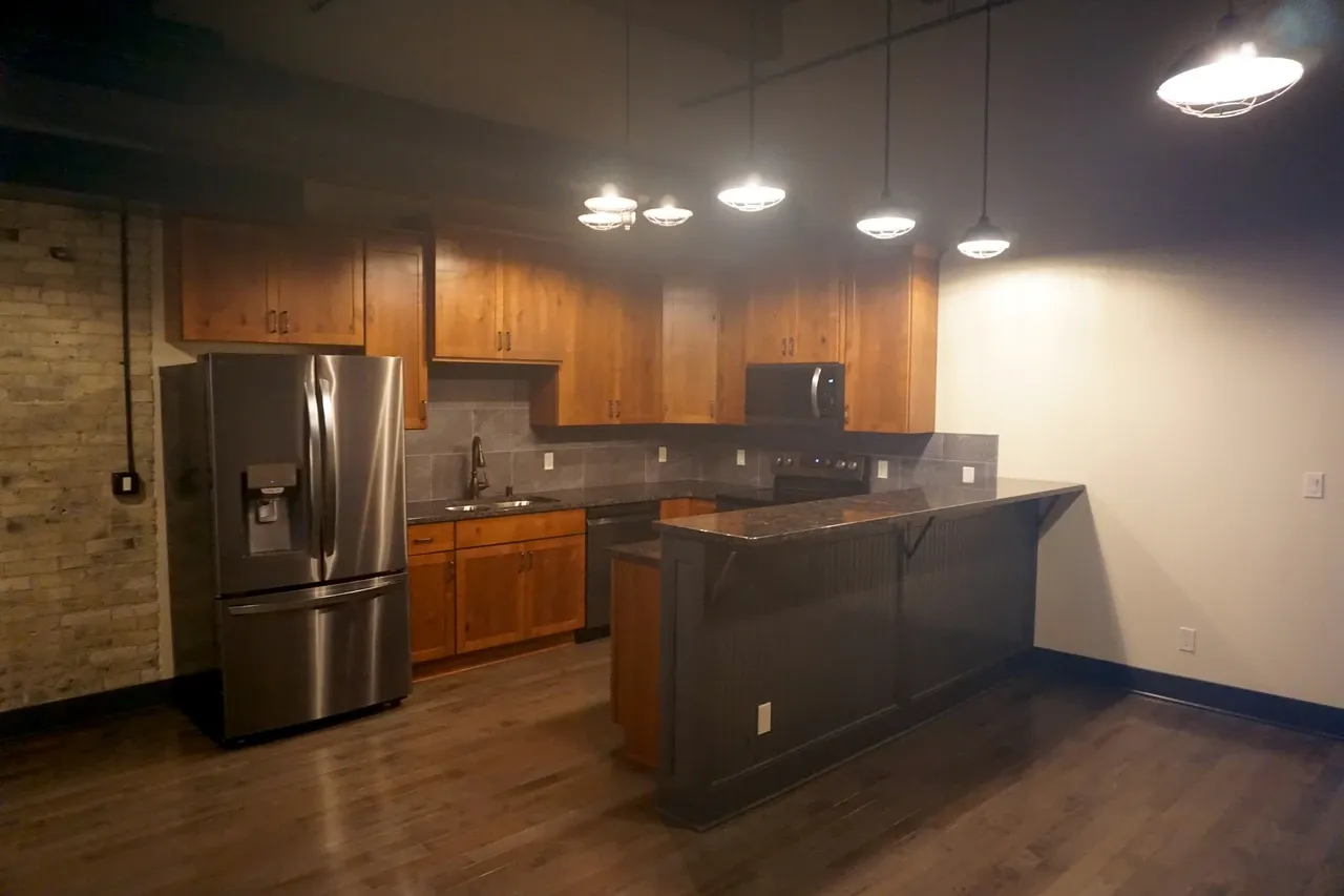 Kitchen cabinets, appliances and a peninsula beneath pendant lights in a Pritzlaff Building apartment in Milwaukee, source-dated September 2025