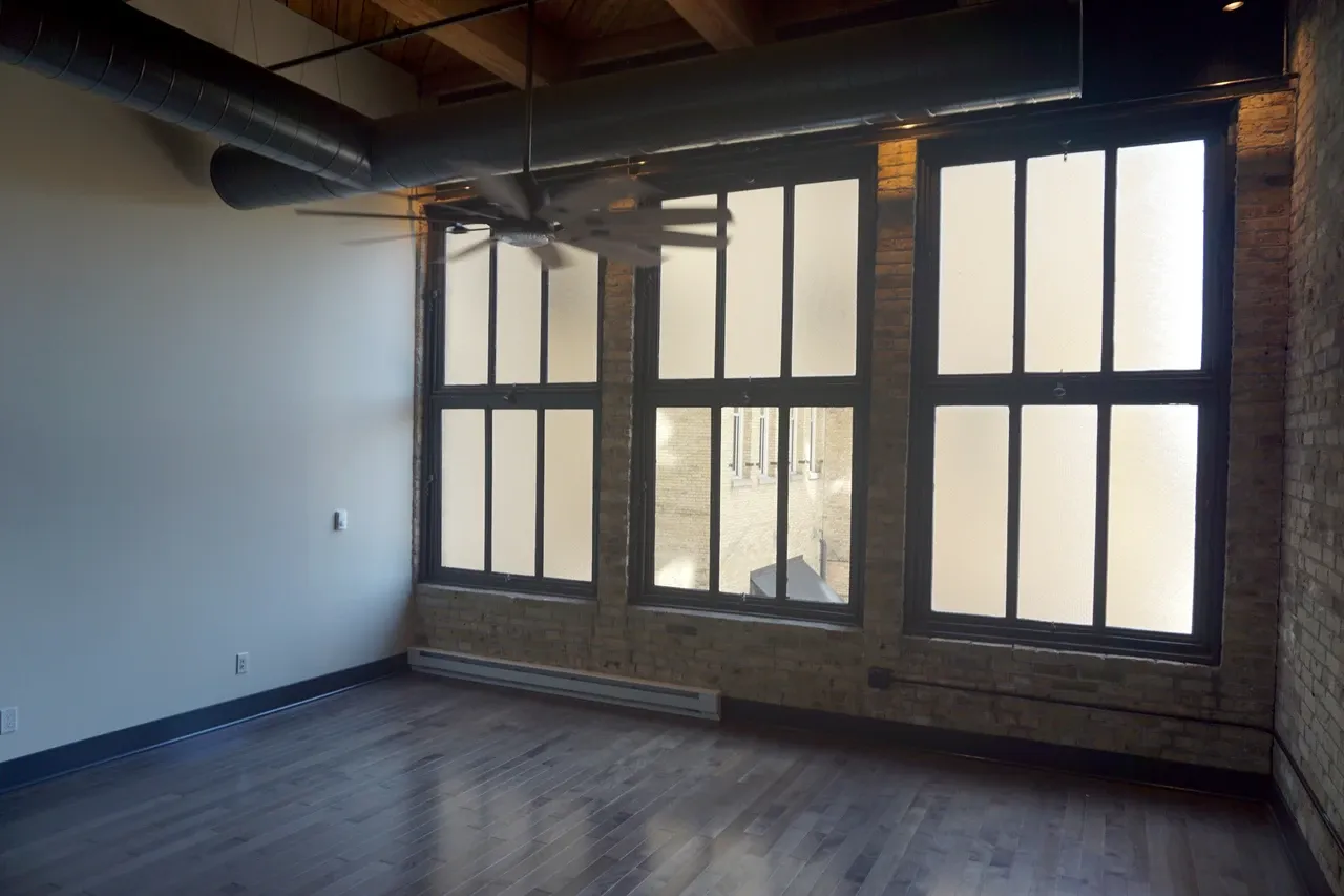 Large windows, brick wall and exposed ceiling structure in a Pritzlaff Building apartment room in Milwaukee, source-dated September 2025