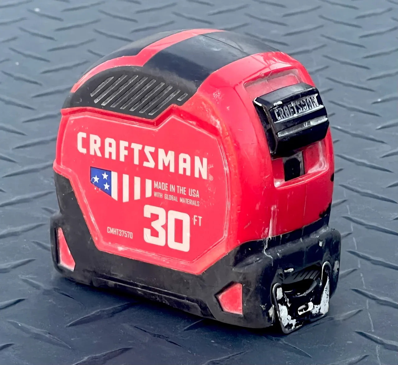 Red and black retractable tape measure resting on a textured grey surface