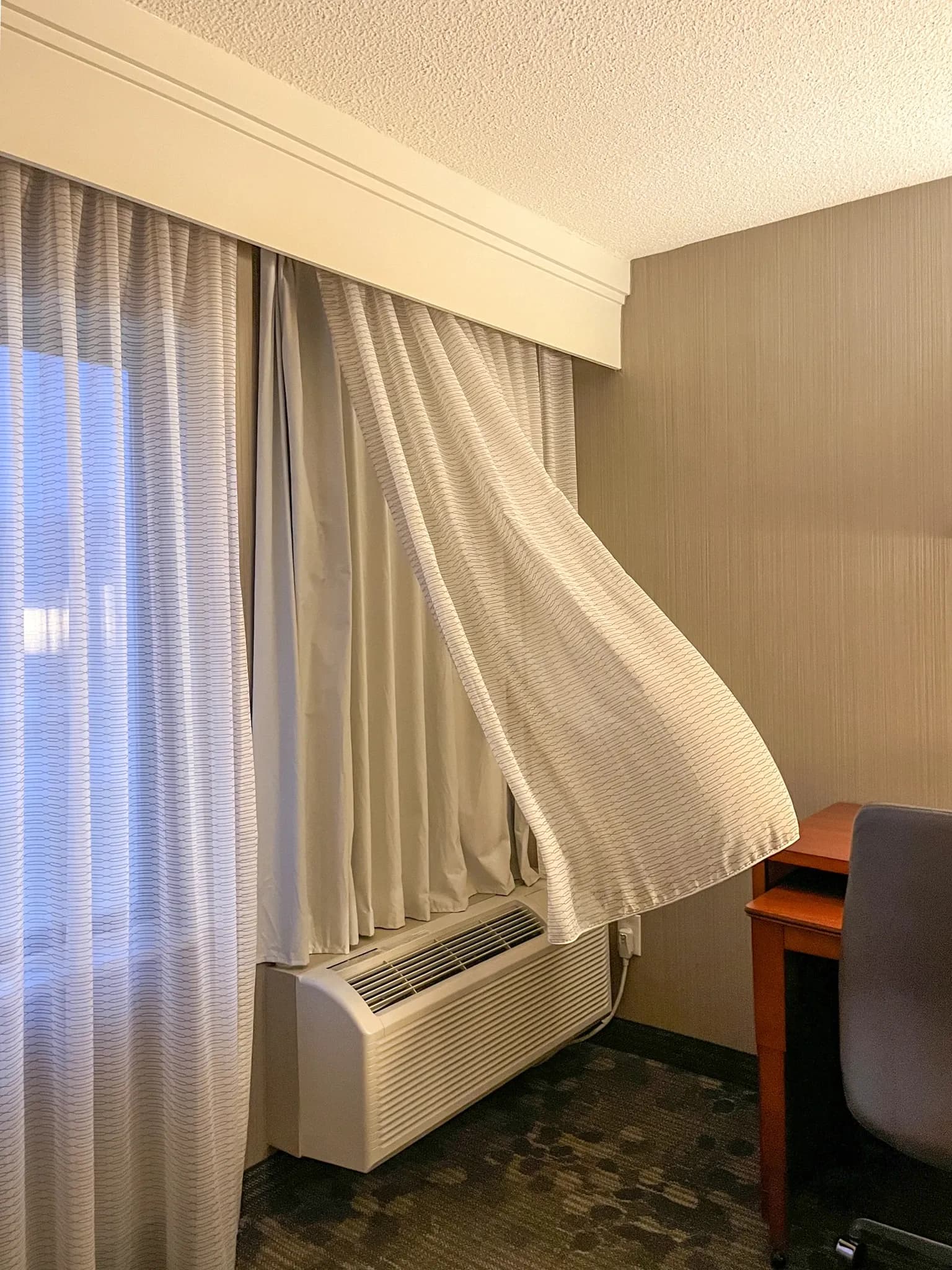 Curtain lifted above a room air conditioner in Westborough, Massachusetts, April 2025