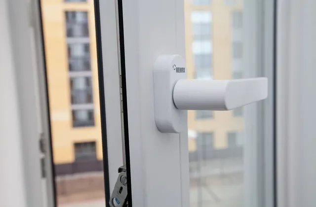 Close view of a white window handle and open sash in an apartment in Tyumen, Russia, March 2016