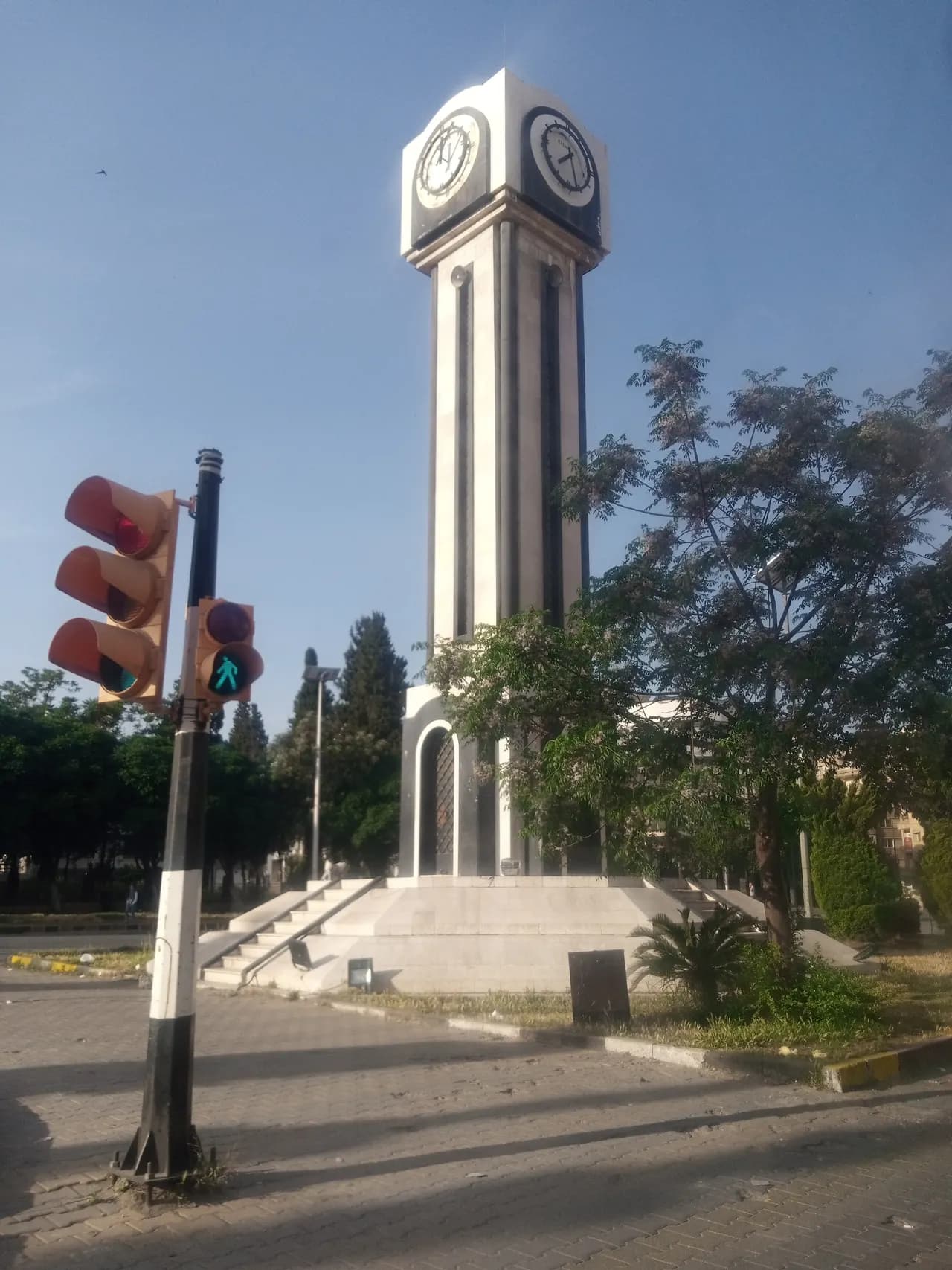 The New Clock Tower in central Homs beside a tree-lined square, photographed in May 2023